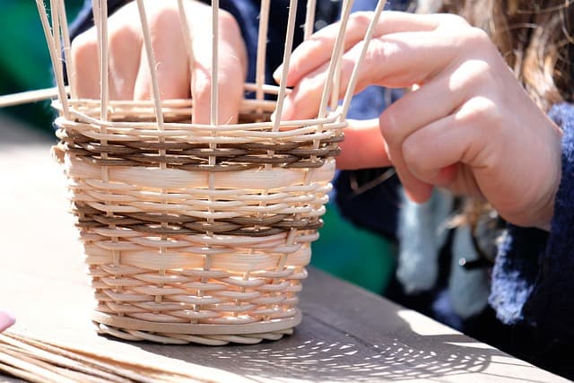 Hände flechten einen traditionellen Weidenkorb